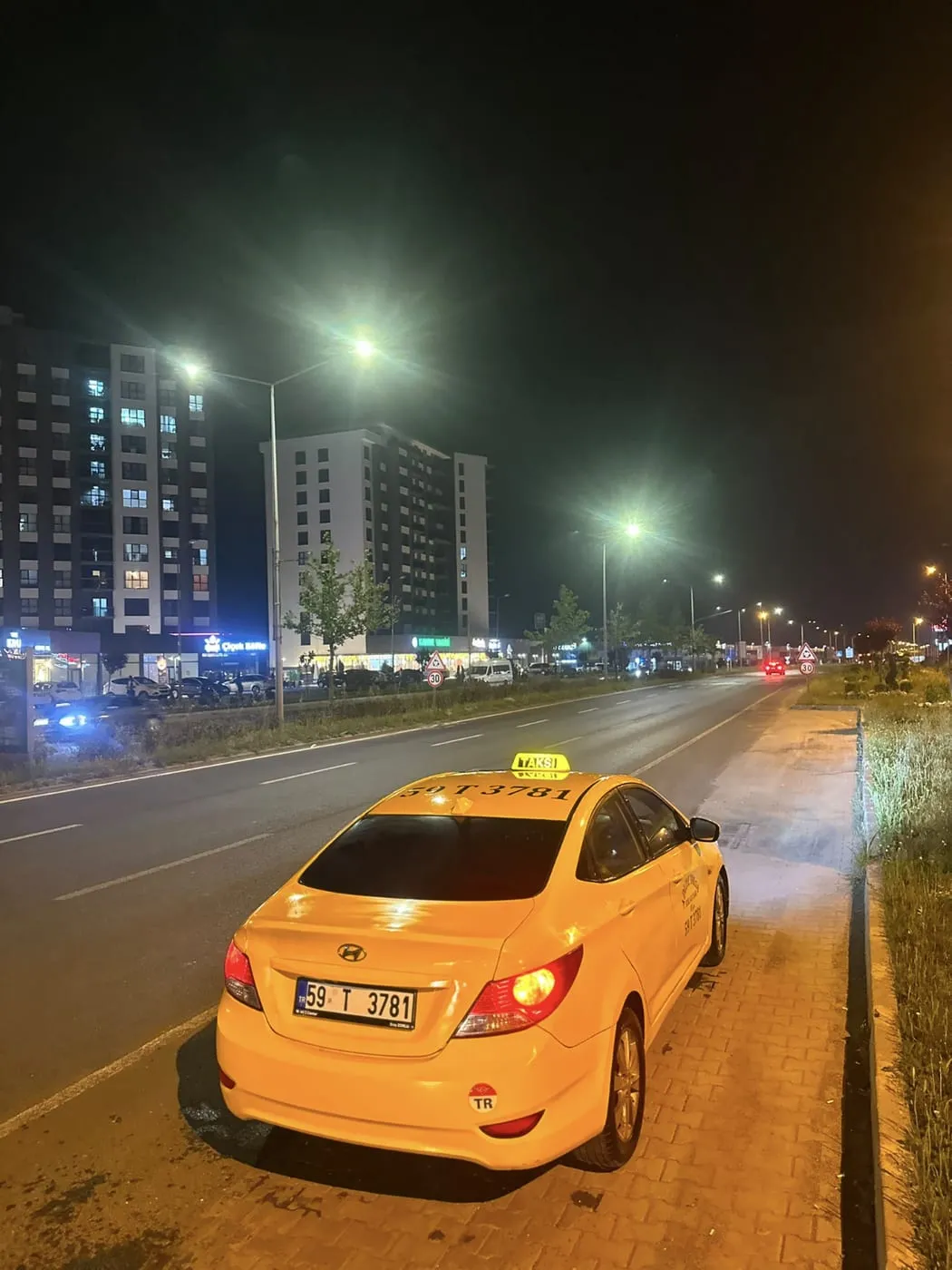 Adliye Taksi aracı gece bulvarda apartmanların önünde yolcu beklerken